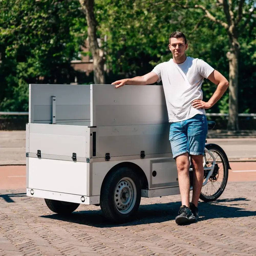 A man leaning on a cargo bike trailer, ready to take the add-ons to the dock