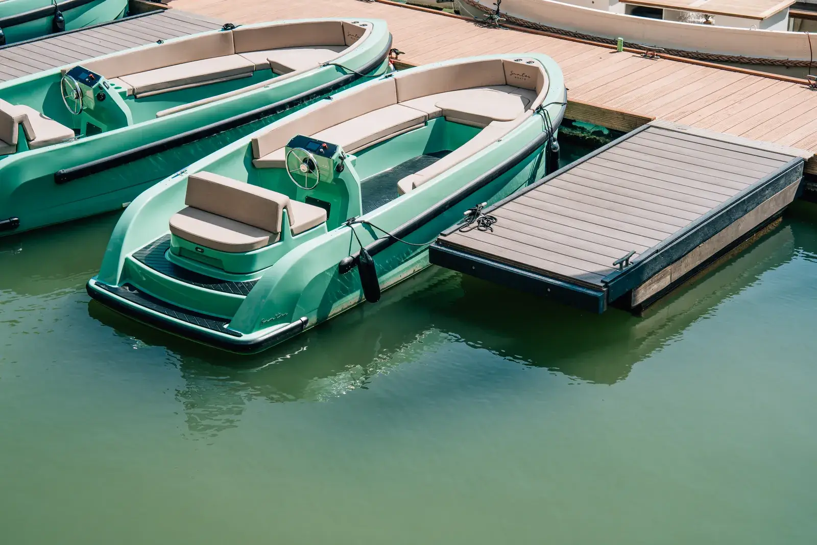 Twee groene huursloepen naast elkaar aan een drijvende steiger